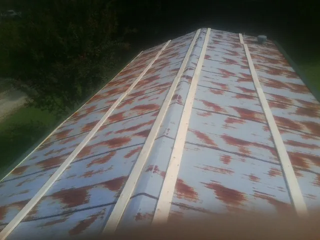 Rusted metal roof panels with new wood purlins before replacement — Storm Damage Roof Repair in Coral by Roofing Brothers