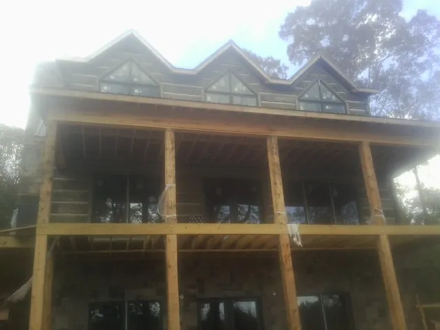 Dormers and porch framing on a large log home under construction — Roof Coating work by our crew in Coral
