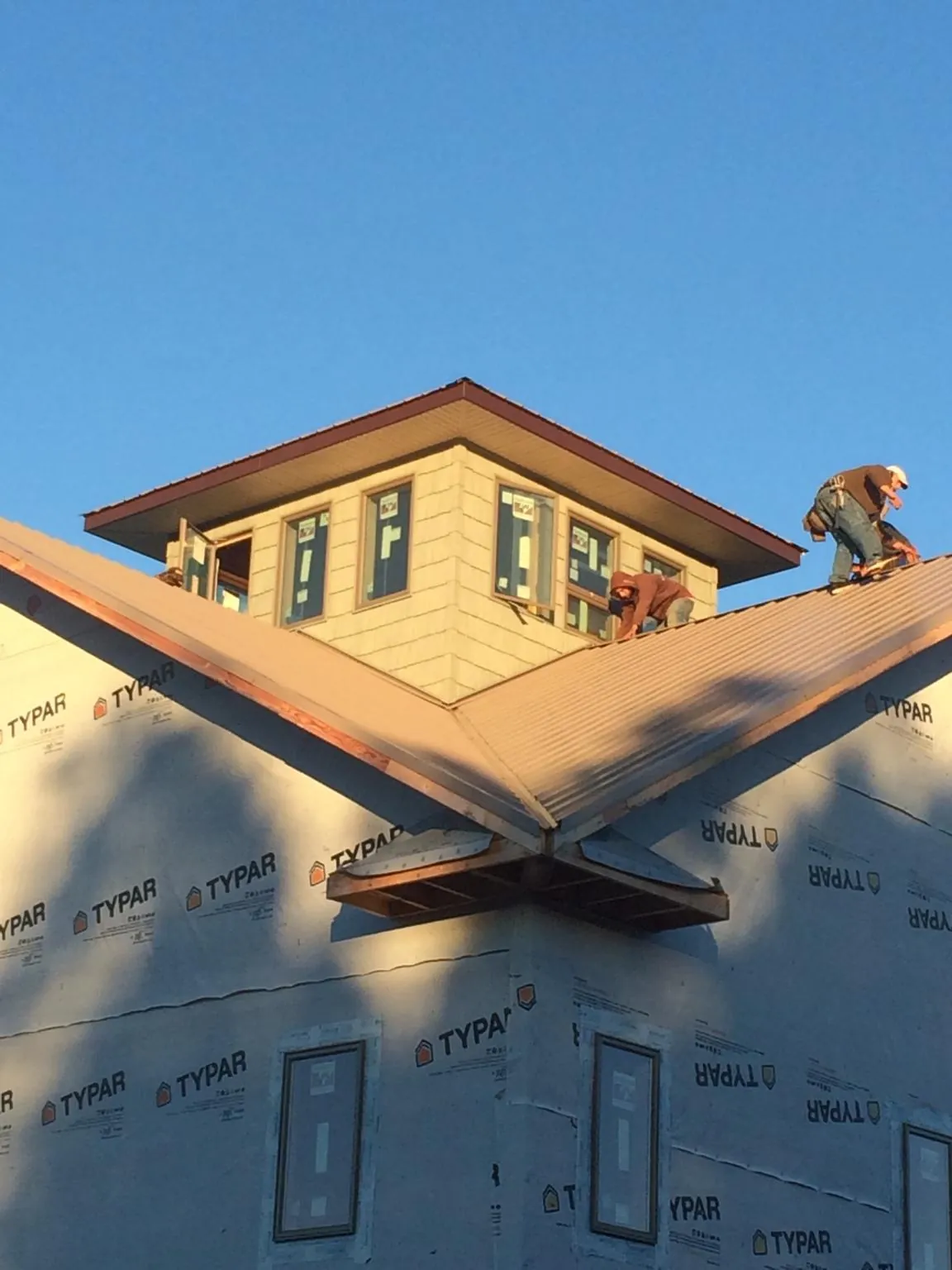 Roofers working around a rooftop cupola on a new metal roof at sunset — Roof Waterproofing in Coral by Roofing Brothers